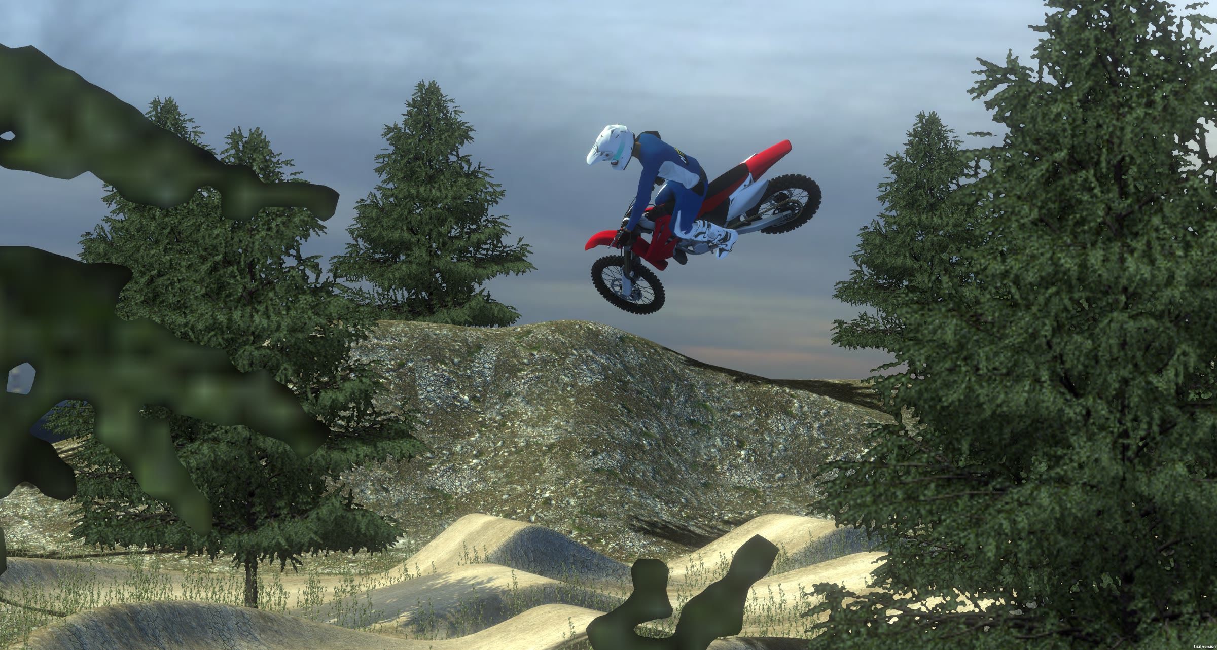 Rider whipping a red dirt bike sideways over a jump in a forest